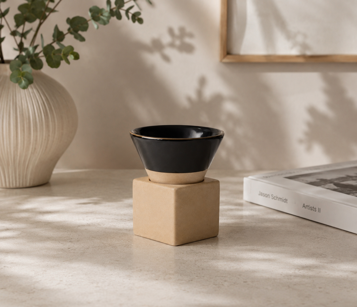 Zwart espressokopje met vierkant blokje van naturel klei op een lichte tafel