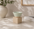 Groen espressokopje met vierkant blokje van naturel klei op een lichte tafel