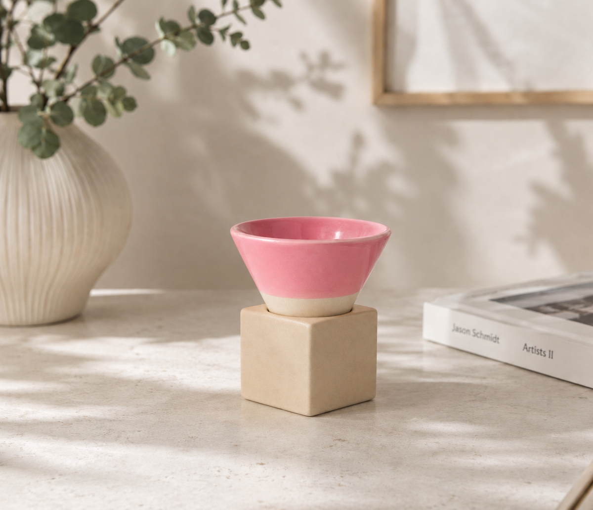 Roze espressokopje met vierkant blokje van naturel klei op een lichte tafel