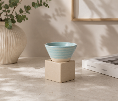 Aqua espressokopje met vierkant blokje van naturel klei op een lichte tafel